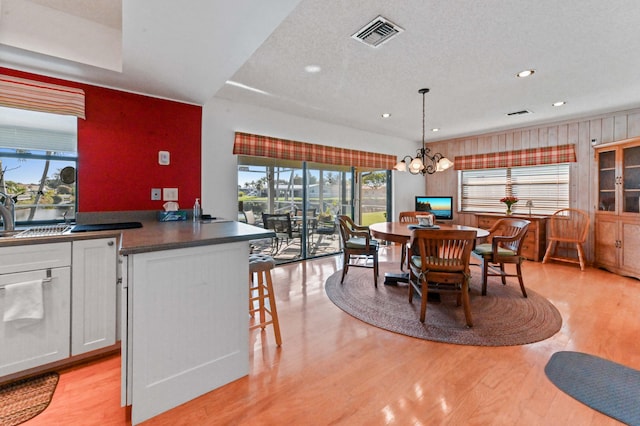 dining area featuring an inviting chandelier, a textured ceiling, and light wood-type flooring