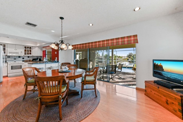 dining space featuring sink, a chandelier, and light hardwood / wood-style floors