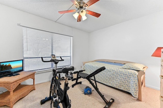 workout area with a textured ceiling, light colored carpet, and ceiling fan