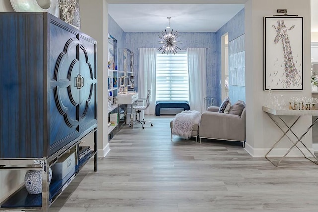 sitting room featuring baseboards, light wood-type flooring, and a chandelier