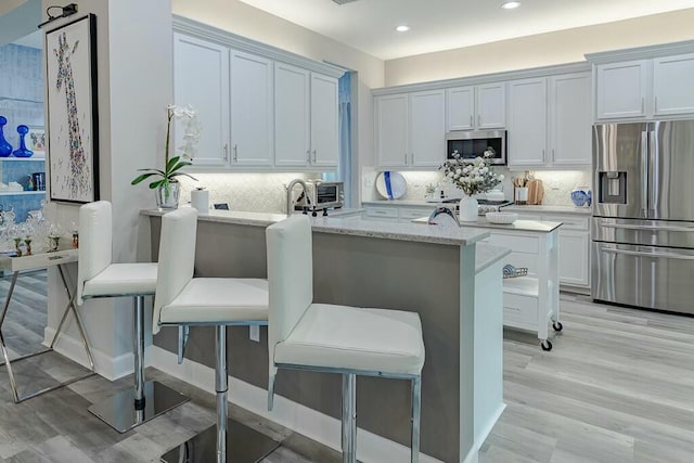 kitchen with decorative backsplash, white cabinets, appliances with stainless steel finishes, and a peninsula