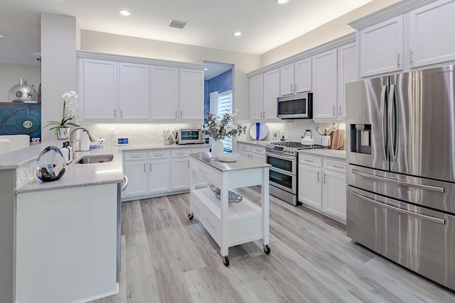 kitchen with a sink, stainless steel appliances, a peninsula, and white cabinets