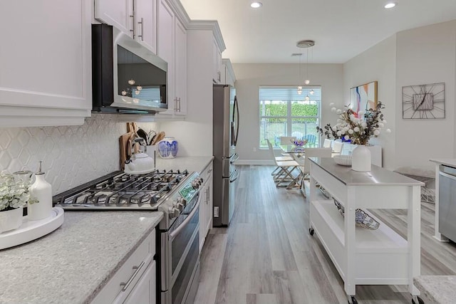 kitchen with tasteful backsplash, light wood finished floors, decorative light fixtures, recessed lighting, and stainless steel appliances