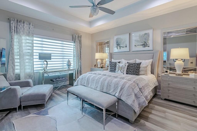 bedroom featuring a raised ceiling, a ceiling fan, and wood finished floors