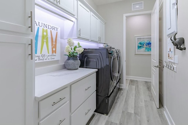 laundry area with visible vents, baseboards, light wood-type flooring, cabinet space, and independent washer and dryer