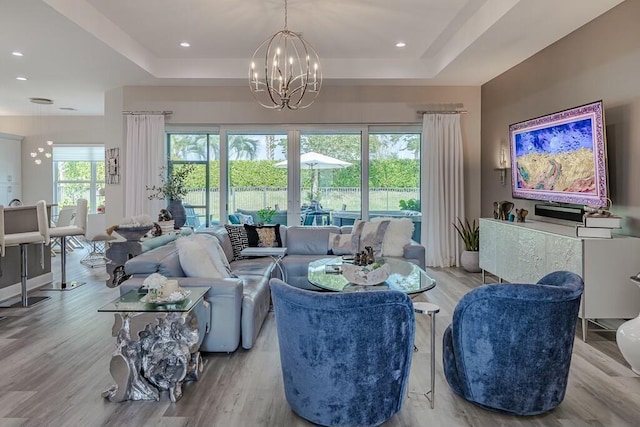 living room with a notable chandelier, a tray ceiling, and wood finished floors