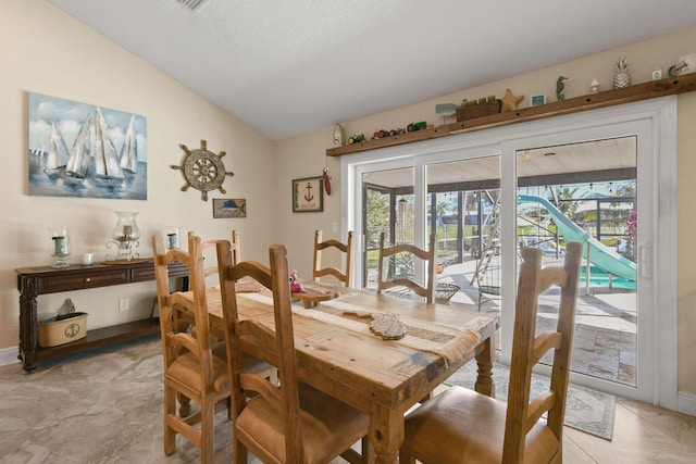 dining room with lofted ceiling, a textured ceiling, and plenty of natural light