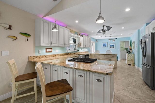 kitchen featuring decorative light fixtures, kitchen peninsula, stainless steel refrigerator, and a kitchen bar