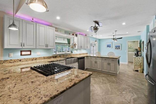 kitchen featuring decorative light fixtures, sink, kitchen peninsula, stainless steel appliances, and light stone countertops