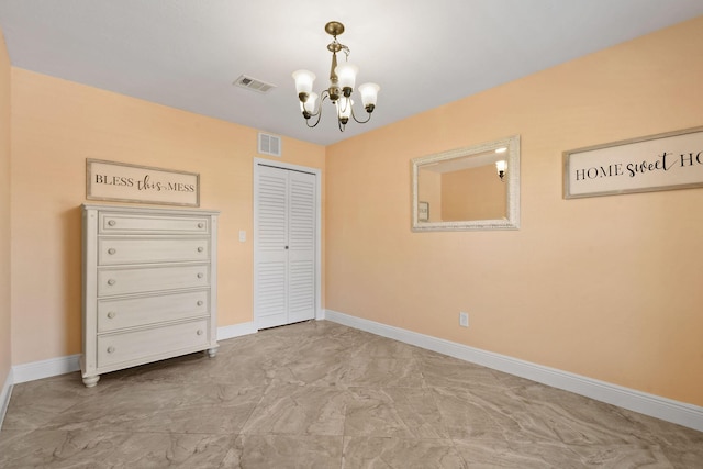 unfurnished bedroom with a notable chandelier and a closet