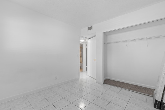 unfurnished bedroom featuring a closet, a textured ceiling, and light tile patterned flooring