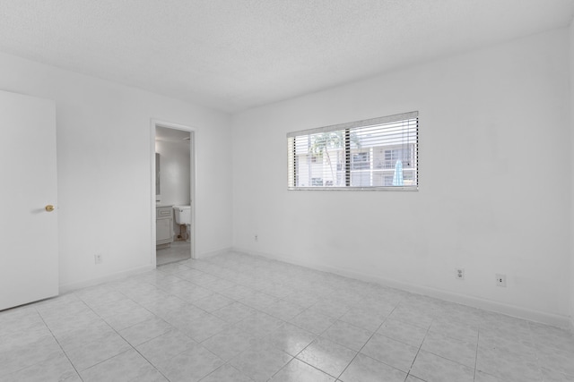 unfurnished bedroom featuring a textured ceiling and ensuite bathroom