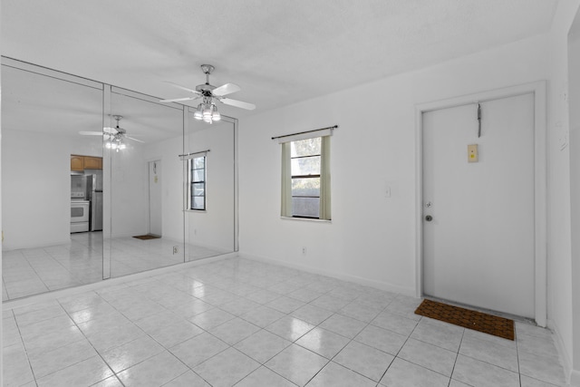 interior space with light tile patterned flooring, ceiling fan, and a textured ceiling