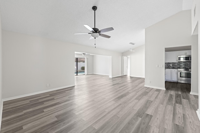 unfurnished living room featuring lofted ceiling, a textured ceiling, light hardwood / wood-style floors, and ceiling fan