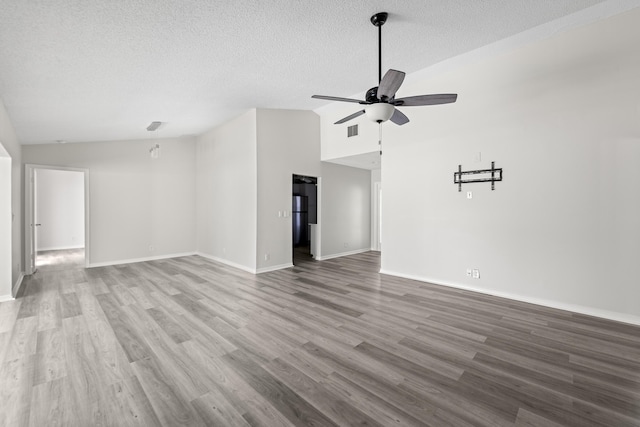 unfurnished living room with vaulted ceiling, hardwood / wood-style floors, a textured ceiling, and ceiling fan