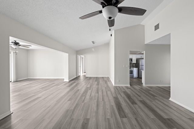 unfurnished living room featuring ceiling fan, wood-type flooring, vaulted ceiling, and a textured ceiling