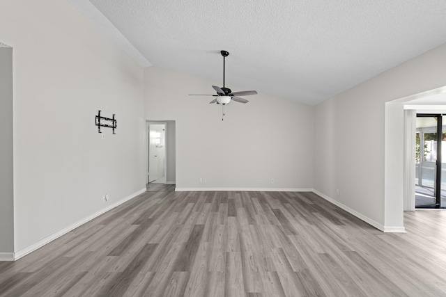 unfurnished living room featuring ceiling fan, lofted ceiling, a textured ceiling, and light hardwood / wood-style floors