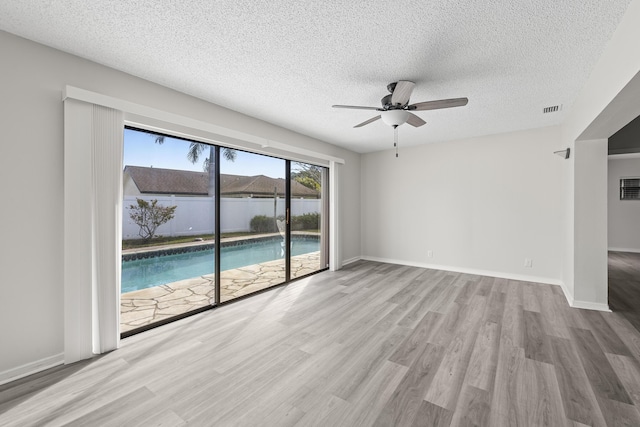 spare room with a textured ceiling, light hardwood / wood-style flooring, and ceiling fan