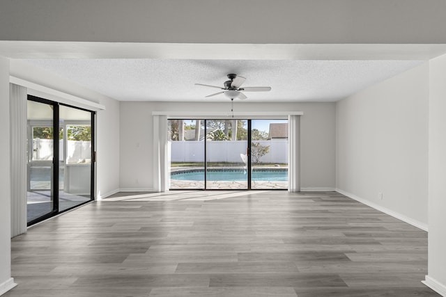 unfurnished room featuring plenty of natural light, light hardwood / wood-style floors, and a textured ceiling