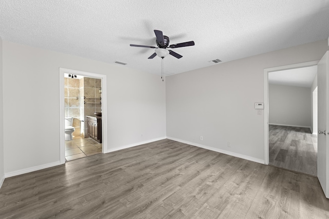 empty room with ceiling fan, hardwood / wood-style flooring, and a textured ceiling