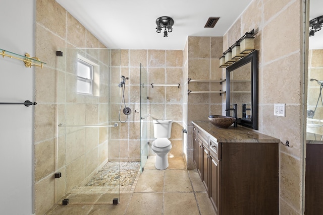 bathroom with tile walls, vanity, toilet, and walk in shower