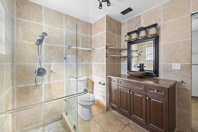 bathroom featuring vanity, toilet, tile walls, and a shower