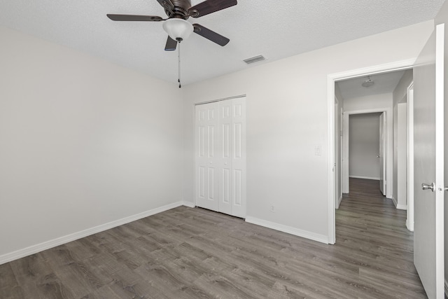 unfurnished bedroom featuring hardwood / wood-style flooring, ceiling fan, a textured ceiling, and a closet