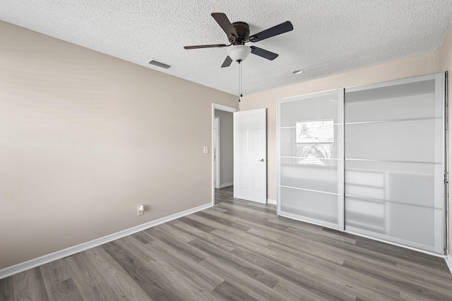 unfurnished bedroom with ceiling fan, wood-type flooring, and a textured ceiling