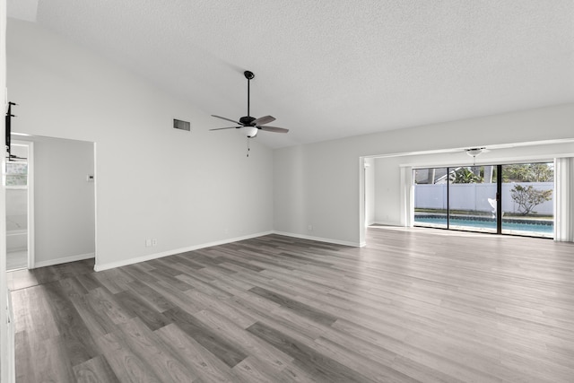 unfurnished living room with hardwood / wood-style floors, a textured ceiling, vaulted ceiling, and ceiling fan