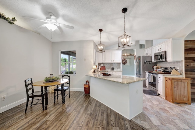 kitchen with appliances with stainless steel finishes, white cabinets, light stone counters, and kitchen peninsula