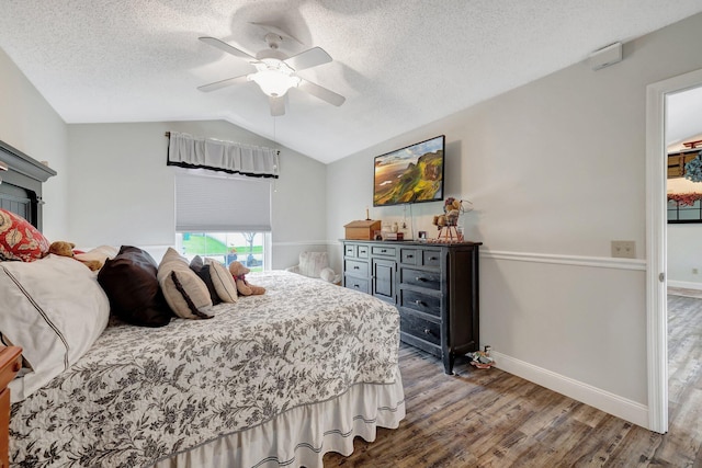 bedroom with hardwood / wood-style floors, vaulted ceiling, a textured ceiling, and ceiling fan