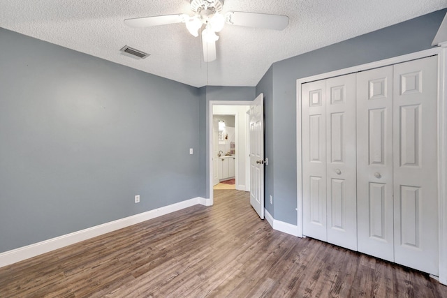 unfurnished bedroom with ceiling fan, dark wood-type flooring, a closet, and a textured ceiling