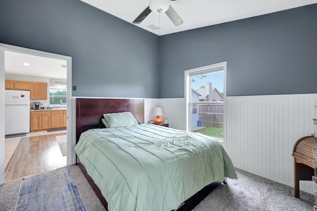 bedroom with white refrigerator, ceiling fan, ensuite bath, and light wood-type flooring