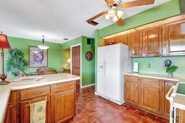 kitchen featuring light countertops, white refrigerator with ice dispenser, stove, and pendant lighting