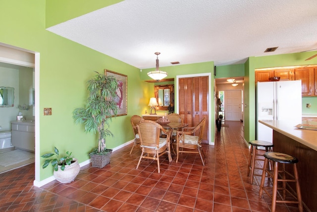 dining space with a textured ceiling and dark tile patterned floors