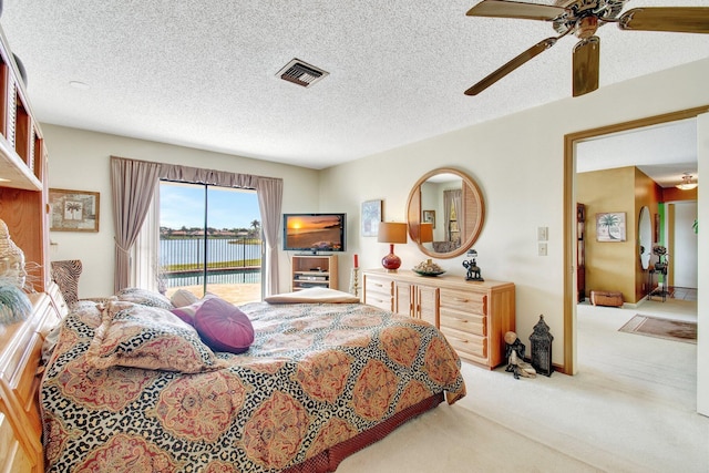 bedroom with a textured ceiling, light carpet, a ceiling fan, visible vents, and access to exterior