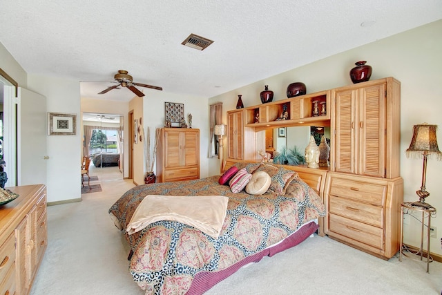 bedroom with ceiling fan, light colored carpet, and a textured ceiling