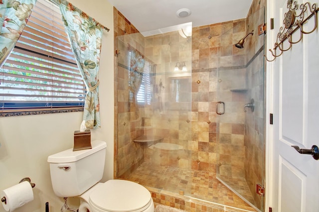 bathroom featuring toilet and a shower with shower door