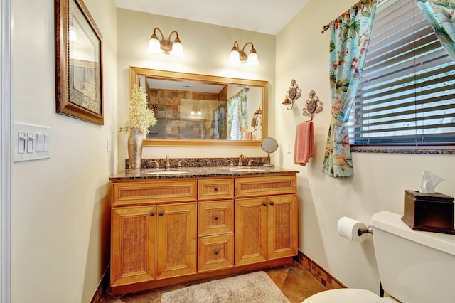 bathroom with tiled shower, vanity, toilet, and tile patterned floors