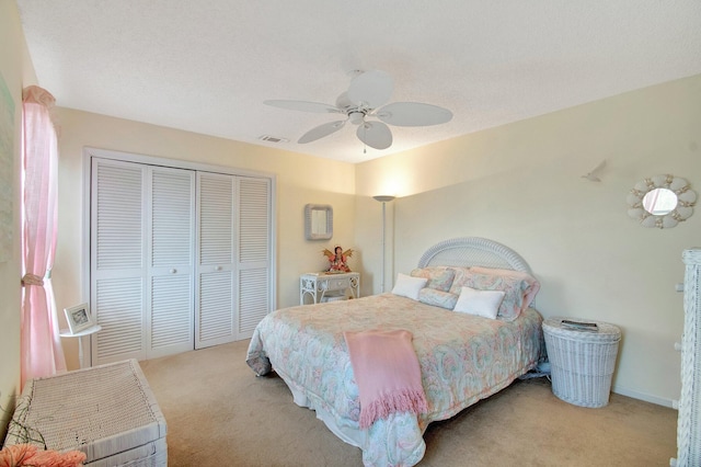 carpeted bedroom with a textured ceiling, ceiling fan, and a closet