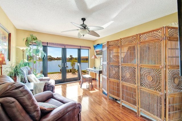 living room featuring wood-type flooring, a textured ceiling, ceiling fan, and french doors