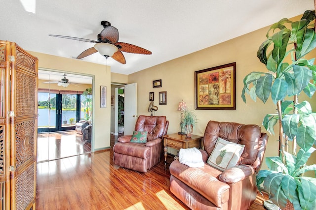 living room featuring light hardwood / wood-style floors, french doors, ceiling fan, and a water view