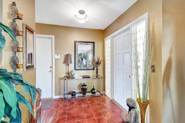 tiled foyer featuring baseboards and a textured ceiling