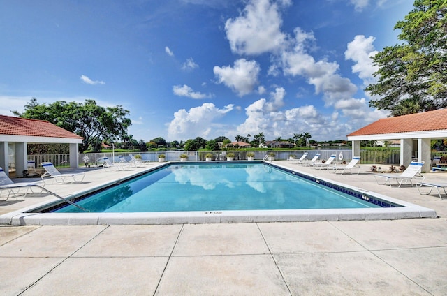 view of swimming pool featuring a patio and a water view