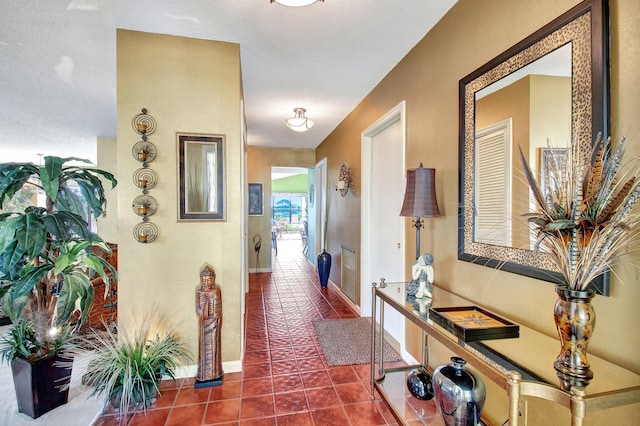 hallway with tile patterned flooring, visible vents, and baseboards