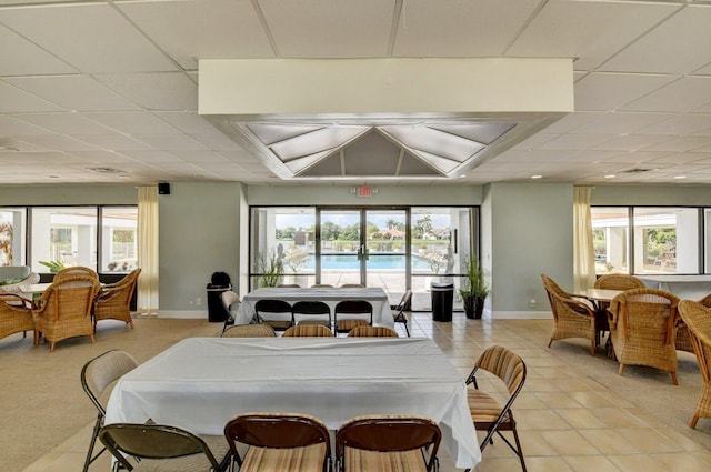 tiled dining room with a paneled ceiling and a wealth of natural light