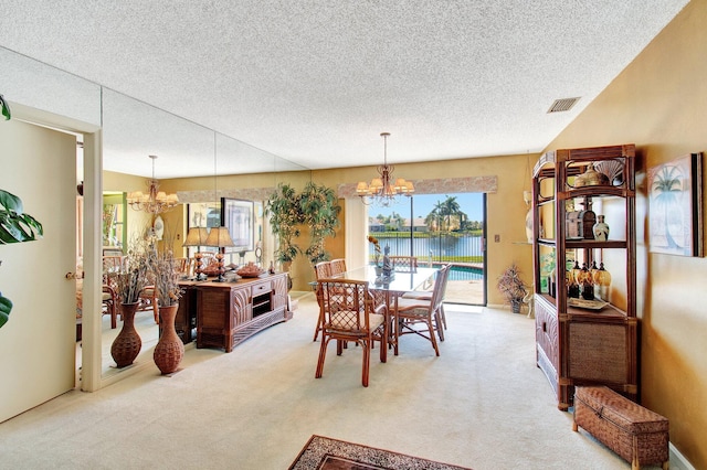 dining area featuring light carpet, a water view, visible vents, and an inviting chandelier