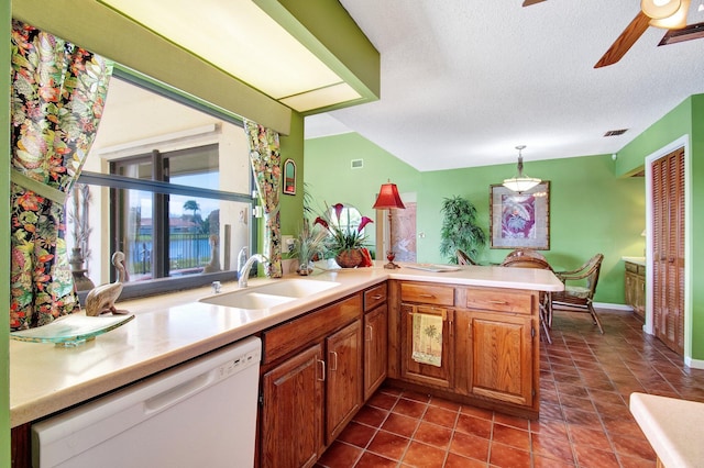 kitchen featuring sink, dishwasher, a textured ceiling, decorative light fixtures, and kitchen peninsula