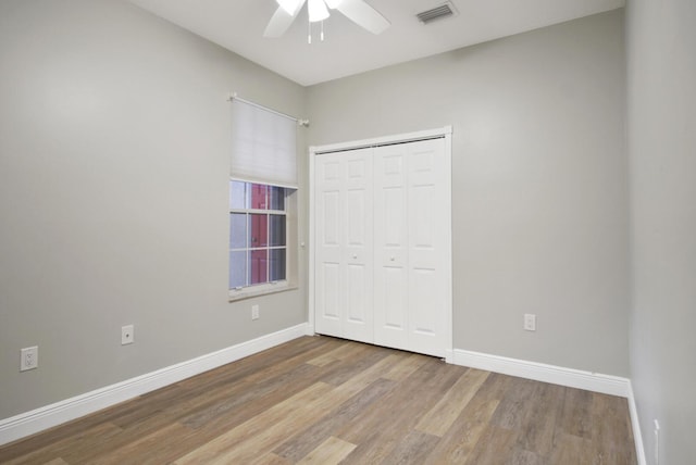 unfurnished bedroom with hardwood / wood-style flooring, ceiling fan, and a closet