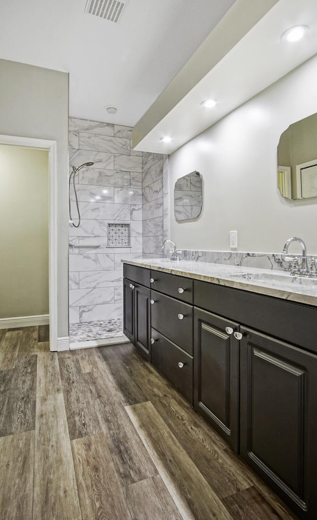 bathroom featuring a tile shower, hardwood / wood-style floors, and vanity